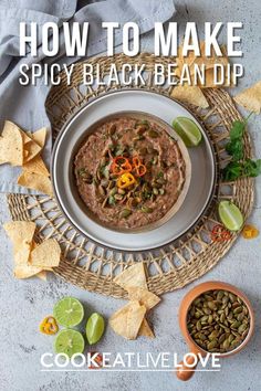 a white bowl filled with black bean dip surrounded by tortilla chips and limes