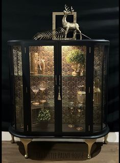 a display case with glass doors and gold trimmings on the front, featuring a deer figurine