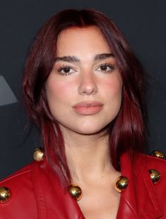 a woman with red hair wearing a red leather jacket and gold buttons on her collar