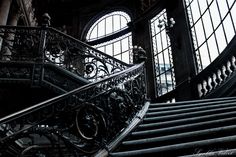 an ornate staircase with wrought iron railing and windows