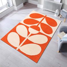 an orange and white rug in a living room with a couch, chair and radiator