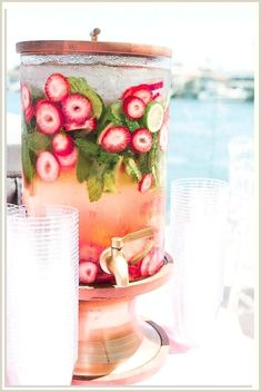 a strawberry and cucumber iced tea is on a table next to some glasses