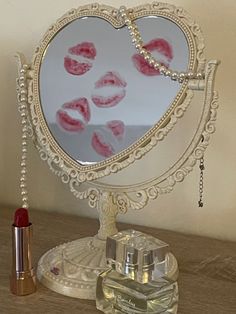 a heart shaped mirror sitting on top of a wooden table next to lipstick and a bottle