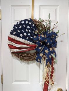 a wreath with an american flag on it hanging from the front door to give as a patriotic decoration