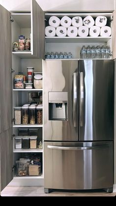 a stainless steel refrigerator in a kitchen with shelves full of food and toilet paper rolls