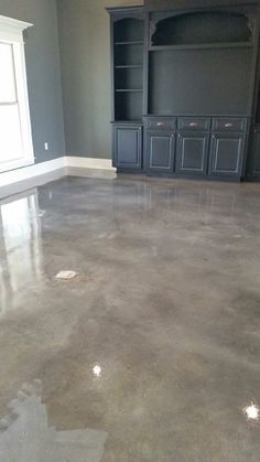 an empty living room with gray walls and concrete flooring is pictured in this image