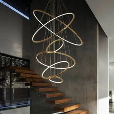 a modern chandelier hanging from the ceiling in a room with stairs and windows