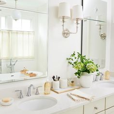 a white bathroom with two sinks and a large mirror above the sink that has flowers in it