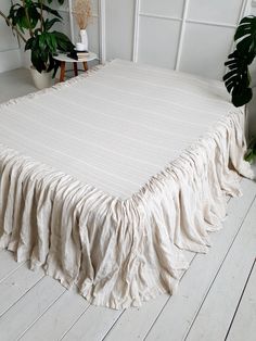 a bed with a white bedspread on top of it next to potted plants