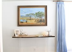 a painting hanging on the wall above a shelf