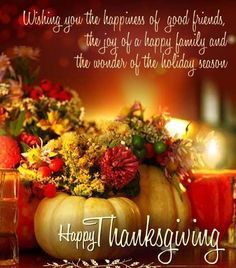 a thanksgiving card with candles and flowers in a pumpkin shaped vase on a table next to a lit candle