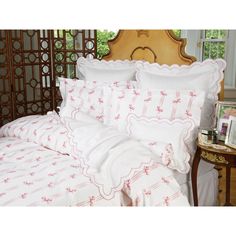 a bed with white and red sheets and pillows on top of it next to a wooden headboard