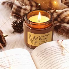 a candle sitting on top of an open book next to some pine cones and candles