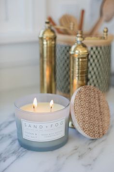 a white candle sitting on top of a counter next to a container filled with scrubs