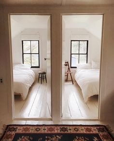 two double doors open to a bedroom with white bedding and rugs on the floor