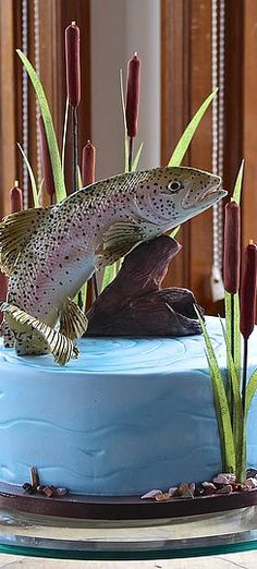 there is a cake decorated with fish and flowers on the top one has grass in front of it