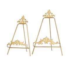 two gold metal stands with ornate designs on them