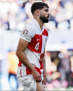 a man with a beard standing in front of a crowd at a soccer game wearing white and red uniforms