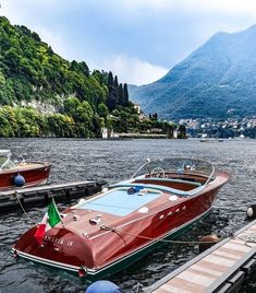 two boats are docked in the water next to some docks and mountains on either side