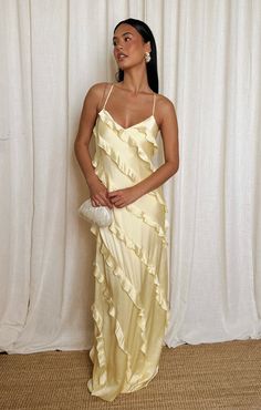 a woman standing in front of a white curtain wearing a dress with ruffles