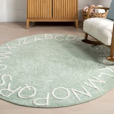 a green rug with white writing on it in front of a wooden cabinet and chair