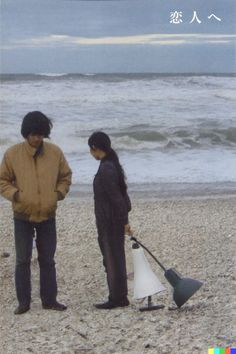 two people are standing on the beach with an umbrella in their hand and one is holding a shovel