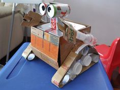 a cardboard box shaped like a dog on top of a blue plastic table with cans