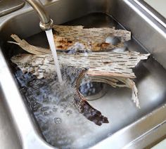 a stainless steel sink with water running from the faucet and wood pieces in it