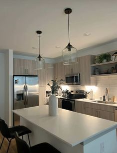 a modern kitchen with stainless steel appliances and white countertops is pictured in this image