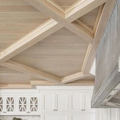 a kitchen with white cabinets and wooden ceiling