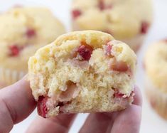 a hand holding a muffin with cranberries and strawberries on the inside