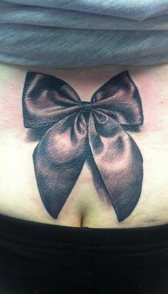 a woman's stomach with a bow tattoo on it