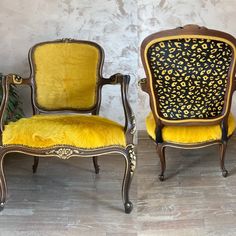 two chairs with leopard print on them sitting next to each other in front of a wall