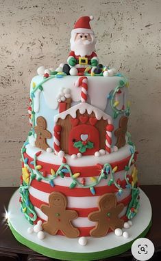 a christmas cake decorated with gingerbreads, candy canes and santa clause on top