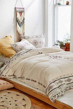 a bedroom with a bed, rugs and pillows on the floor in front of a window