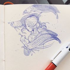 a drawing of a girl holding a fish on top of a piece of paper next to a pen