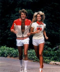 a man and woman are running down the street in matching outfits, with trees behind them