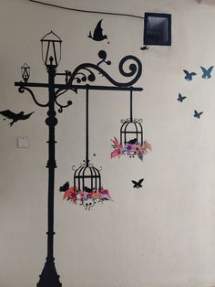 a street light with birds flying around it and butterflies on the wall behind it,