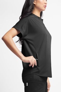 So many graceful details! This top looks like a button-up, but pops easily over your head. Ruching softens the silhouette front and back. Dolman sleeves feel so comfortable. WhisperLite may be your coolest-feeling scrubs ever. Feather light poplin with wicking and 4-way stretch that also repels lint, fur, and hair. And with extra chic, feminine styling, they look cool too. • Oversized fit • V-neck with banded collar • Total of 3 pockets • 2 large onseam front pockets • 1 cell pocket in right poc Crew Neck Athleisure Tops For Work, Athleisure Crew Neck Top For Work, Oversized Tops With Pockets And Shirttail Hem, Black Workwear Tops With Pockets, Casual Stretch Top With Pockets, Athleisure Tops With Pockets For Everyday, Versatile Black Tops With Pockets, Versatile Black Top With Pockets, Oversized Workwear Tops With Pockets