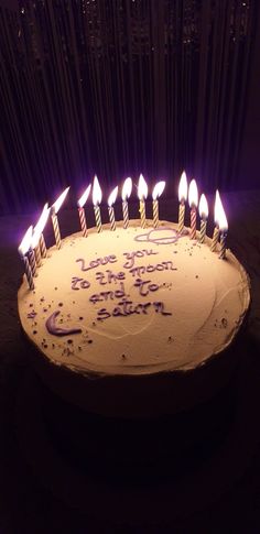 a birthday cake with lit candles that says i love you to the moon and back