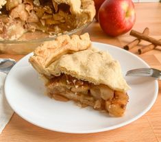 a piece of pie sitting on top of a white plate next to an apple pie