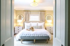 an open door leading to a bedroom with a white bed and blue upholstered bench