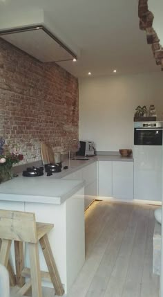 a kitchen with an oven, counter and stools next to a brick wall in the background