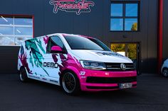 a pink and white van parked in front of a building