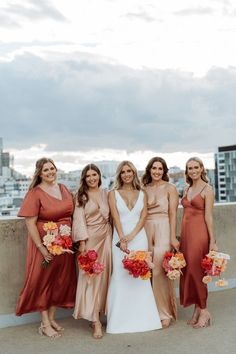 the bride and her bridesmaids pose for a photo in front of the city skyline