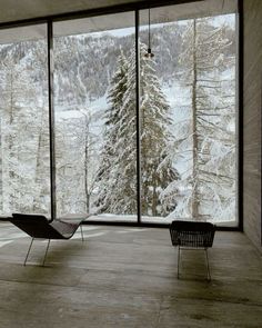 an empty room with large windows overlooking the snowy mountains and pine trees in winter time