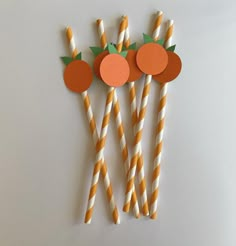 three orange and white striped straws with apples on them, one is made out of paper