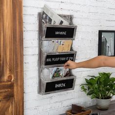 there is a person that is pointing at the newspaper rack on the wall with magazines in it