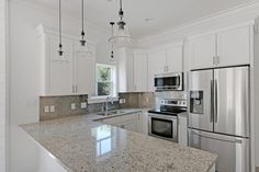 a large kitchen with white cabinets and stainless steel appliances, including an island countertop