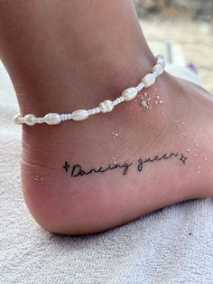 a woman's foot with the words dancing queen written on it and pearls around her ankles